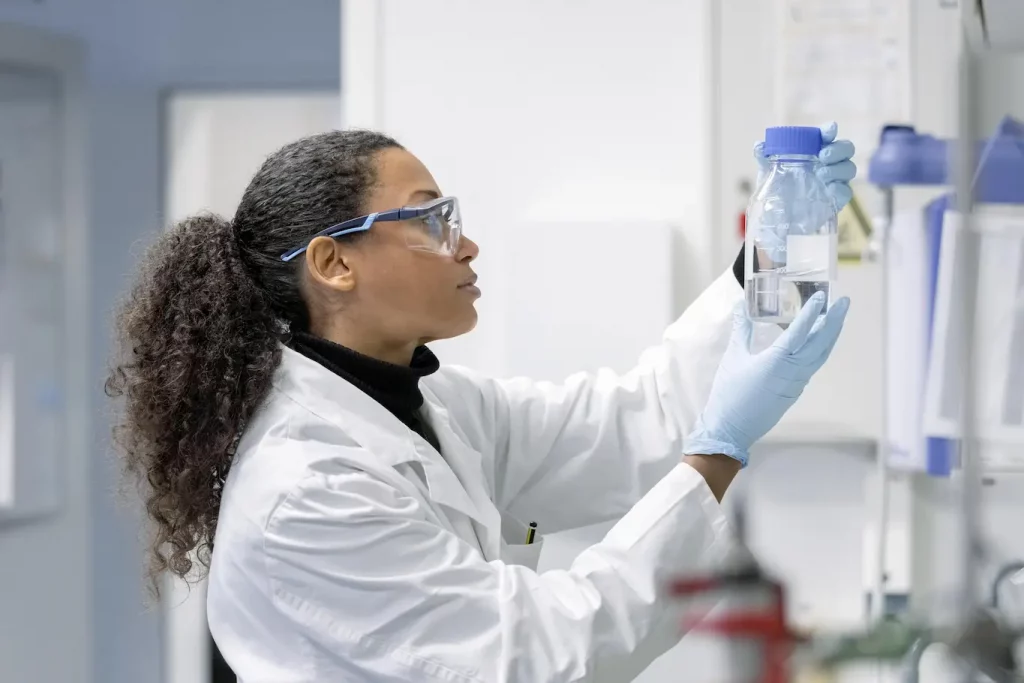 Person in a lab coat holding a laboratory bottle